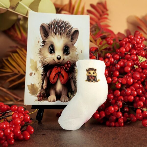Pair of Poky Hedgehog Kids Socks next to a vibrant illustration of Poky, the cute Afita Collection character, with red autumn berries.